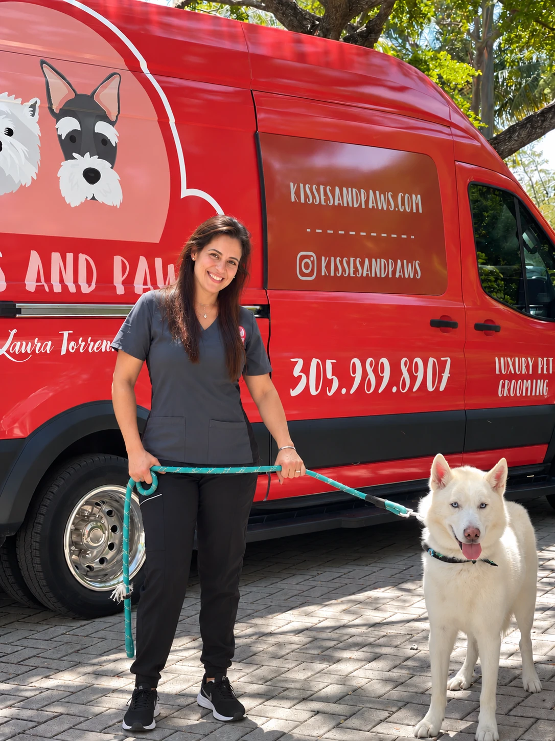 Laura Torrente with a white husky beside the red Kisses and Paws mobile grooming vehicle